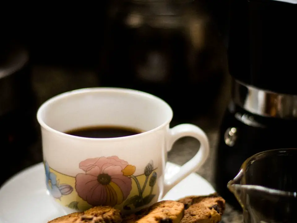 Šoljica crne kafe na tanjiriću, uz nju keksići